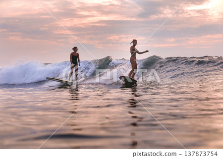 Dynamic Surfing Scene With Women And Companions In Evening Glow Dynamic Surfing Scene With Women And Companions In Evening Glow 137873754