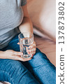 Woman sits in bed and holds glass of clean water in her hands. World Water Day. 137873802