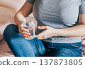 Woman sits in bed and holds glass of clean water in her hands. World Water Day. 137873805