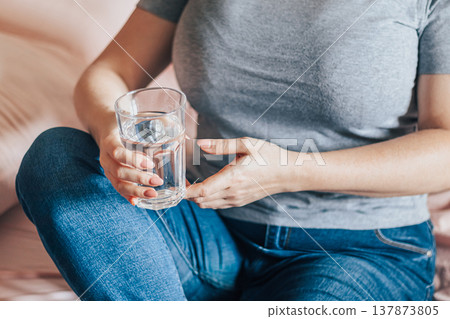 Woman sits in bed and holds glass of clean water in her hands. World Water Day. 137873805