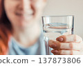 Woman holding glass of clean water in her hands. Portrait of a young smiling red-haired woman. World Water Day. 137873806