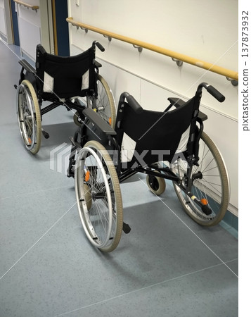 Two empty wheelchairs in a bright hospital corridor Two empty wheelchairs in a bright hospital corridor 137873932