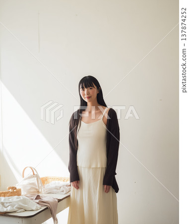 日本女性站在室內，穿著自然時尚的全套服裝。 137874252