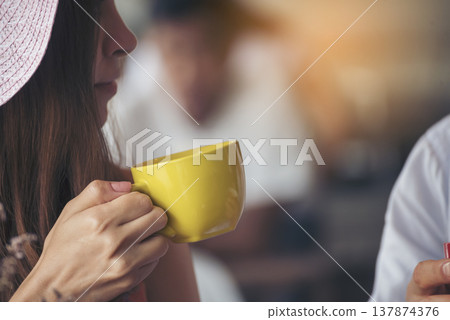 Asian Woman drink black coffee hand holding cup at green garden cafe. Young woman smile face love drink coffee. Beauty woman drinking black tea in coffee shop holding freshness cup. Women lifestyle Asian Woman drink black coffee hand holding cup at green garden cafe. Young woman smile face love drink coffee. Beauty woman drinking black tea in coffee shop holding freshness cup. Women lifestyle 137874376