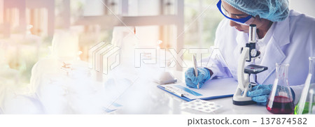 Banner Asian woman scientist hand write note research in medical lab look at science microscope. Panorama biology chemistry lab. Asian Female technician laboratory using microscope with copy space Banner Asian woman scientist hand write note research in medical lab look at science microscope. Panorama biology chemistry lab. Asian Female technician laboratory using microscope with copy space 137874582