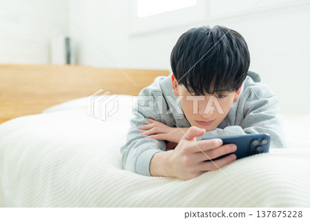 Men watching smartphones in bed Men watching smartphones in bed 137875228