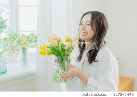 A woman holding a vase of tulips 137875448