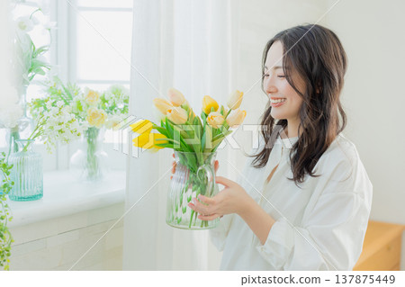A woman holding a vase of tulips 137875449