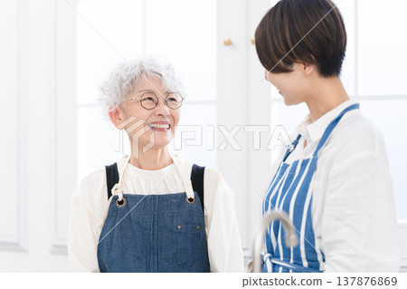 年輕女子和老年婦女站在廚房做飯的形象 年輕女子和老年婦女站在廚房做飯的形象 137876869