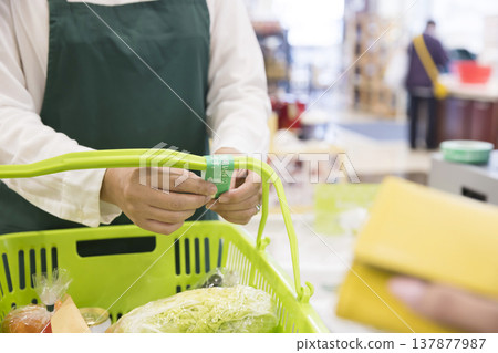 店員在超市收銀台膠帶上包裹購買的膠帶 店員在超市收銀台膠帶上包裹購買的膠帶 137877987