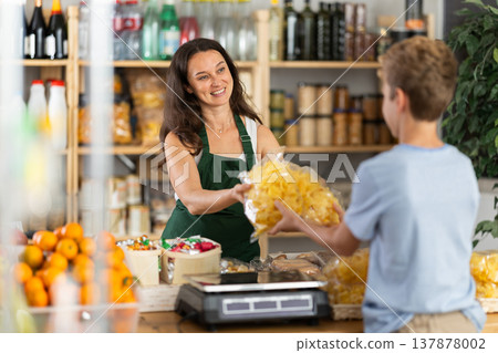 Female seller offers chips to boy buyer 137878002