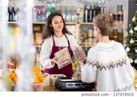 Female employee sells cookies to teen boy on Christmas Eve. Female employee sells cookies to teen boy on Christmas Eve. 137878020