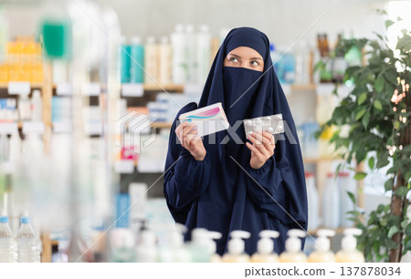 Young Muslim woman customer choosing pills in box in drugstore Young Muslim woman customer choosing pills in box in drugstore 137878034