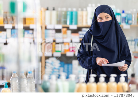 Muslim woman with prescription looking for medications in pharmacy Muslim woman with prescription looking for medications in pharmacy 137878043