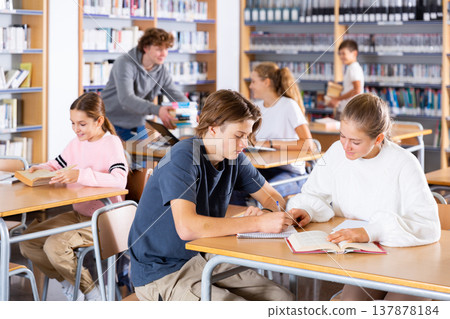 Cute tween girl and intelligent boy studying together in library, reading books Cute tween girl and intelligent boy studying together in library, reading books 137878184
