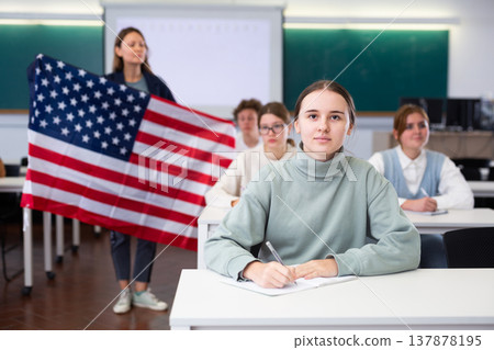 Teacher stands behind students with flag of USA 137878195
