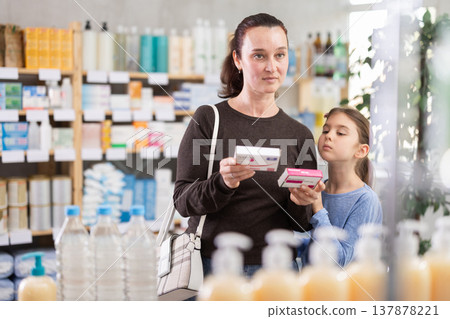 Woman with daughter choosing paracetamol in pharmacy 137878221