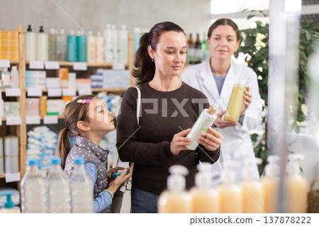 Caring mother choosing dermatologically tested shampoo for daughter Caring mother choosing dermatologically tested shampoo for daughter 137878222