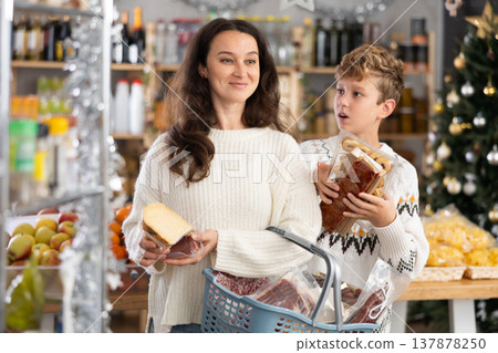 Adult woman with son choosing products in grocery store Adult woman with son choosing products in grocery store 137878250