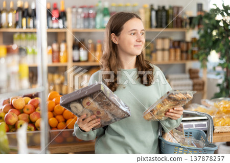 Teen girl selects suitable product from cookies assortment Teen girl selects suitable product from cookies assortment 137878257