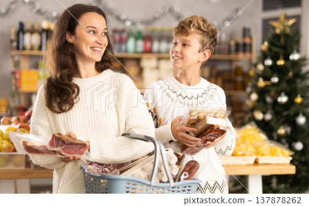 Teenage son and mother choose different products together in grocery supermarket Teenage son and mother choose different products together in grocery supermarket 137878262