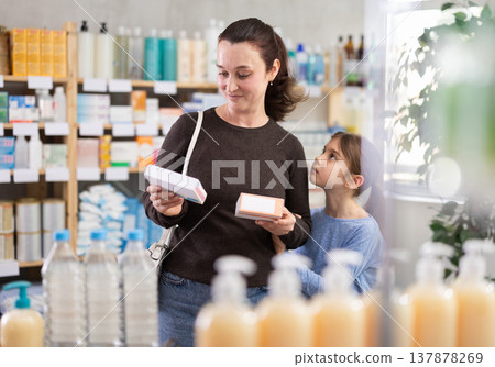 Woman with daughter choosing pills in pharmacy Woman with daughter choosing pills in pharmacy 137878269