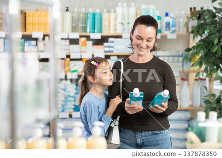 Woman with schoolgirl daughter are busy choosing mouthwash at pharmacy 137878350