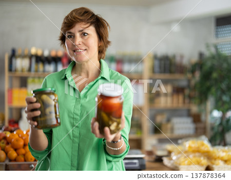 Woman chooses tomatoes and cucumbers in a marinade Woman chooses tomatoes and cucumbers in a marinade 137878364