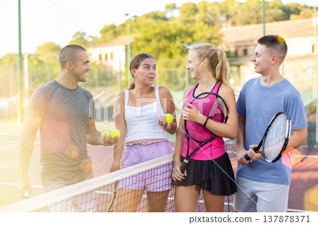 Men and women having conversation on outdoor tennis court Men and women having conversation on outdoor tennis court 137878371