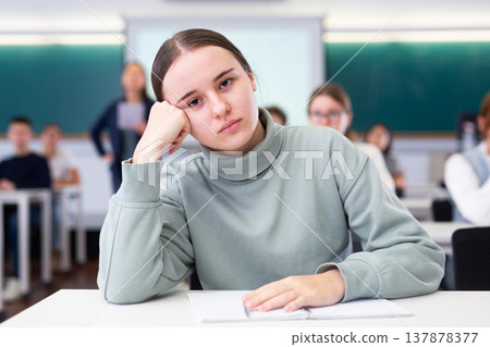 Female college student sitting at desk in classroom Female college student sitting at desk in classroom 137878377