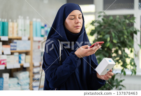 Young woman in hijab scans qr code of pills Young woman in hijab scans qr code of pills 137878463