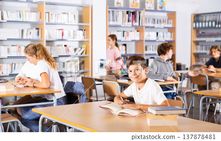 Portrait of a schoolboy preparing for an exam in school library Portrait of a schoolboy preparing for an exam in school library 137878481