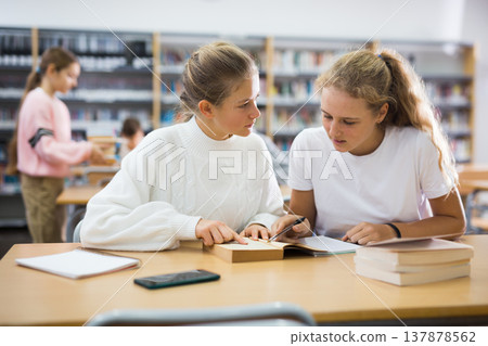Girls doing homework together in library 137878562