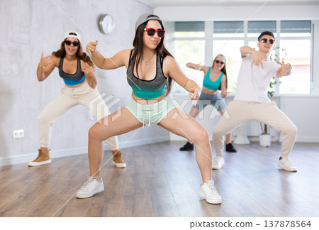 Group of young girls in dark glasses and ball cap and guy dance jazz-funk in fitness club. 137878564