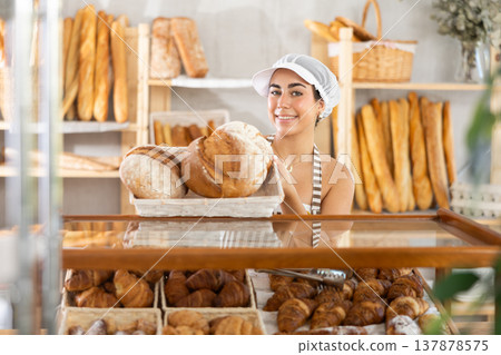 Young saleswoman displays bread in square wicker basket 137878575