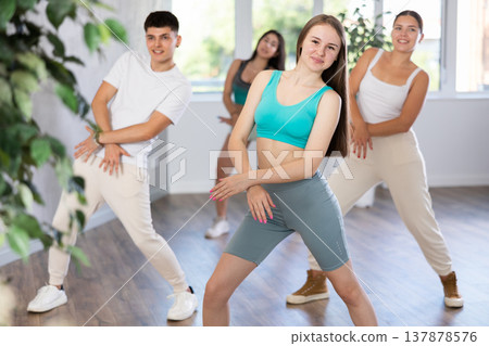 Girl teen perform choreographic exercise and teach energetic house dance with friends Girl teen perform choreographic exercise and teach energetic house dance with friends 137878576