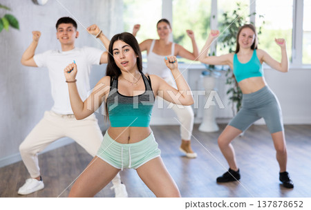 Expressive Hispanic teenage girl dancing hip-hop with group in studio Expressive Hispanic teenage girl dancing hip-hop with group in studio 137878652