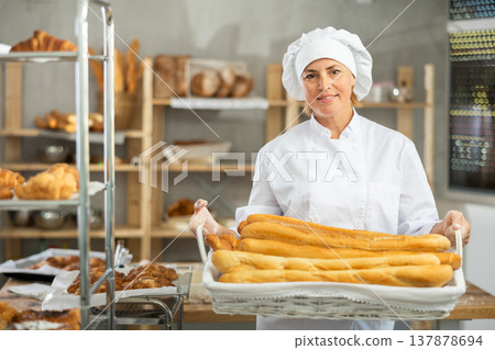 Adult female baker with basket of baguettes Adult female baker with basket of baguettes 137878694