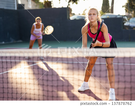 Caucasian woman wearing in pink t-shirt and skirt playing tennis match during training 137878762
