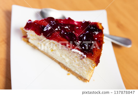 Piece of cranberries cheesecake, drizzled with jam on top 137878847