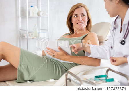 Middle-aged woman signing contract before having a medical operation in cosmetology clinic Middle-aged woman signing contract before having a medical operation in cosmetology clinic 137878874