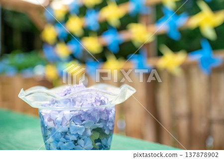 Hydrangeas and pinwheels floating in a transparent glass bowl – a refreshing image of early summer. Hydrangeas and pinwheels floating in a transparent glass bowl – a refreshing image of early summer. 137878902