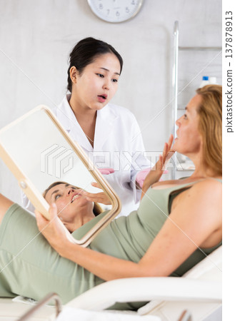 Professional cosmetologist talking about anti-aging skincare to patient Professional cosmetologist talking about anti-aging skincare to patient 137878913