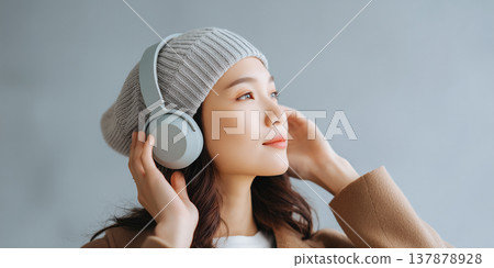 一位女士戴著針織帽和耳機，正在欣賞音樂。 137878928