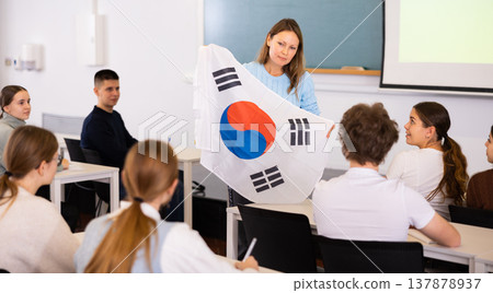 Adult female teacher showing South Korea flag to students 137878937