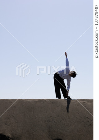 Silhouette of a man standing on the sand Silhouette of a man standing on the sand 137879487