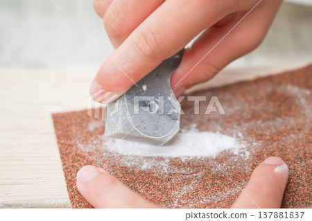 Making magatama (comma-shaped beads): A child's hands filing down a stone. 137881837
