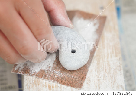 Polishing a magatama (comma-shaped bead) with sandpaper 137881843