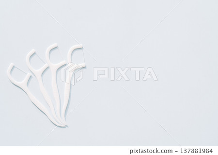 Group of white dental floss picks on light blue background with large copy space, dental care concept 137881984