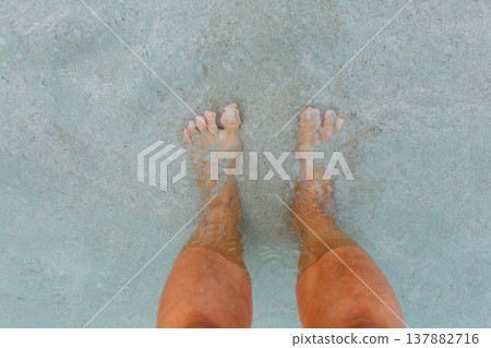 high angle view of woman bare feet standing in the sea on the sand high angle view of woman bare feet standing in the sea on the sand 137882716